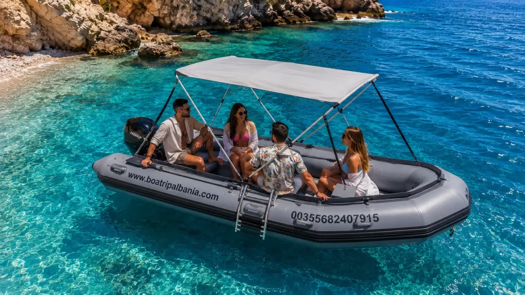 Family enjoying a small rental boat in Himare, Albania with crystal clear blue sea.
