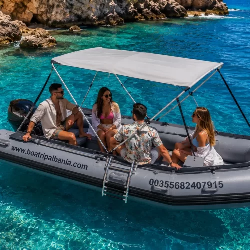 Family enjoying a small rental boat in Himare, Albania with crystal clear blue sea.
