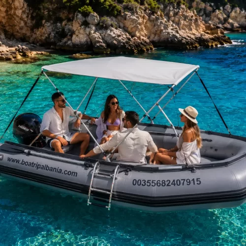 People enjoying a self-drive rental boat in Himare with turquoise sea and rocky coastline.